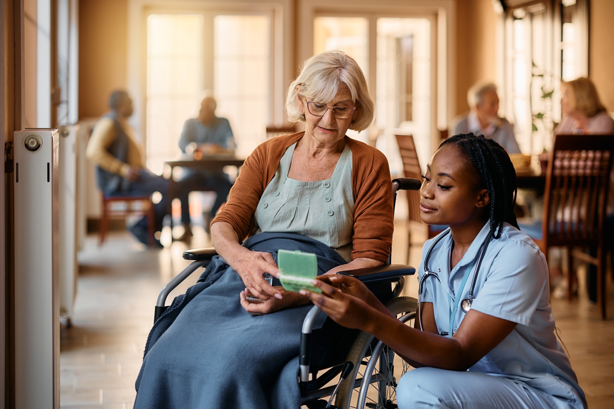 Educational Tips 66 Young black nurse giving pills to senior woman in wheelchair at nursing home.